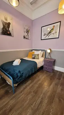 a bedroom with a bed and a purple wall at Lansdowne Simply Stay in Redruth
