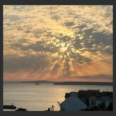 a sunset over the water with the sun in the sky at Uno St Ives - Boutique Luxury Accommodation in St Ives
