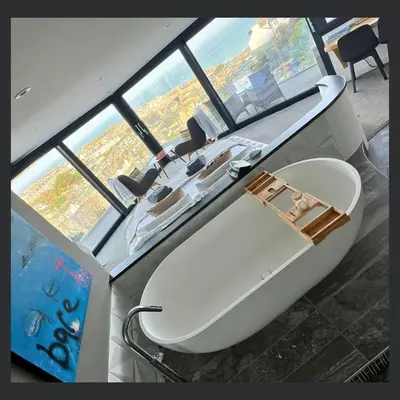 a large bath tub in a room with windows at Uno St Ives - Boutique Luxury Accommodation in St Ives