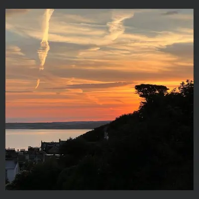 a sunset over a body of water with a tree at Uno St Ives - Boutique Luxury Accommodation in St Ives