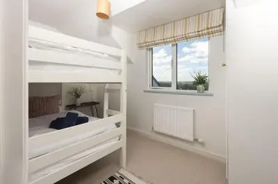 a bedroom with white bunk beds and a window at Westaway House in Port Isaac