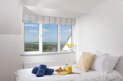 a white bed with a window and towels on it at Westaway House in Port Isaac