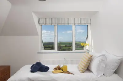 a bedroom with a white bed with a window at Westaway House in Port Isaac