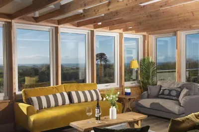 a living room with windows and a yellow couch at Westaway House in Port Isaac