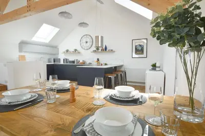 a dining room with a wooden table and a kitchen at Birch House in St. Agnes