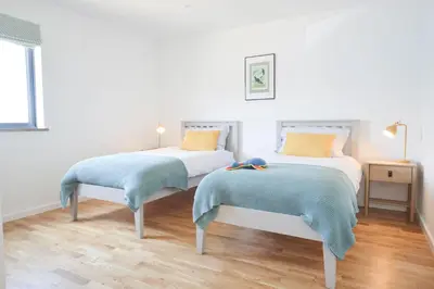 a bedroom with two beds with blue and yellow pillows at Birch House in St. Agnes