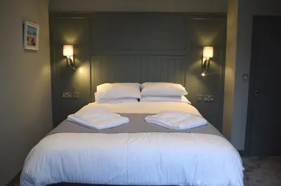a large bed with white sheets and pillows on it at Crown Inn in Penzance