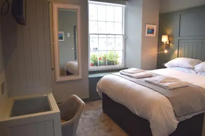 a bedroom with a bed and a mirror and a window at Crown Inn in Penzance