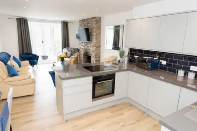 a kitchen with white cabinets and a living room at Modern House in Looe, Near Beach and Bars with Great Views and free access to a nearby Indoor Swimming Pool in Looe