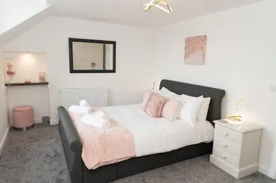 a bedroom with a bed with pink and white pillows at Modern House in Looe, Near Beach and Bars with Great Views and free access to a nearby Indoor Swimming Pool in Looe