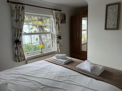 a bedroom with a large bed with towels on it at Primrose Cottage in Hayle