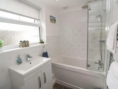 a white bathroom with a sink and a shower at Primrose Cottage in Hayle