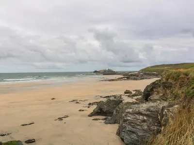 a beach with rocks and the ocean on a cloudy day at Primrose Cottage in Hayle