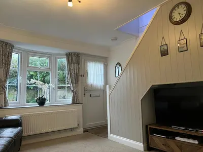 a living room with a staircase and a television at Primrose Cottage in Hayle
