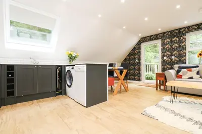 a kitchen and living room with a washing machine at Robin's Nest at The Shire Inn in Camborne
