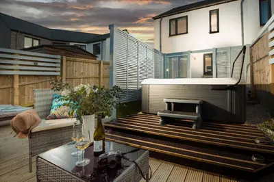 a patio with a grill and a table on a deck at Wish You Were Here - Hot Tub - Free Parking & Free WiFi in Newquay