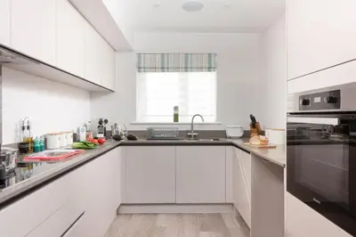 a white kitchen with white cabinets and a sink at Wish You Were Here - Hot Tub - Free Parking & Free WiFi in Newquay