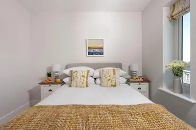 a white bedroom with a large bed and two windows at Wish You Were Here - Hot Tub - Free Parking & Free WiFi in Newquay