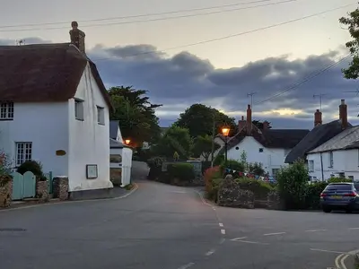 a street in a small village with houses and a car at Wish You Were Here - Hot Tub - Free Parking & Free WiFi in Newquay