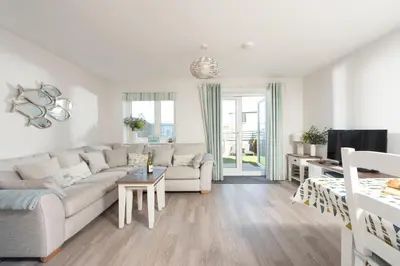 a living room with a couch and a table at Wish You Were Here - Hot Tub - Free Parking & Free WiFi in Newquay
