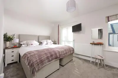 a white bedroom with a large bed and a window at Wish You Were Here - Hot Tub - Free Parking & Free WiFi in Newquay