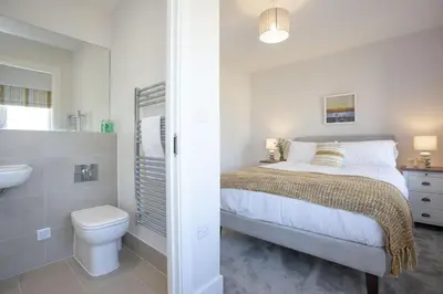 a bedroom with a bed and a toilet and a sink at Wish You Were Here - Hot Tub - Free Parking & Free WiFi in Newquay