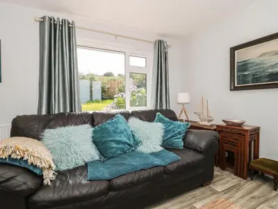 a living room with a brown leather couch with blue pillows at Honeycroft in Boscastle