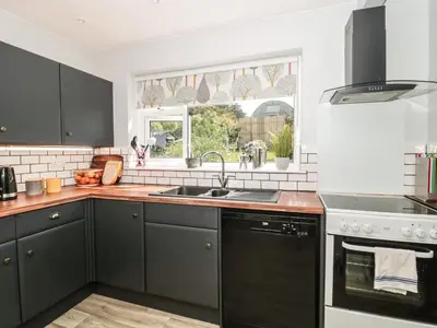 a kitchen with black cabinets and a sink at Honeycroft in Boscastle