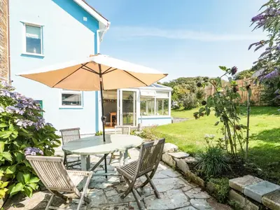 a patio with a table and chairs and an umbrella at Honeycroft in Boscastle