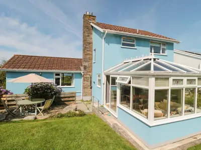 a house with a conservatory and a garden at Honeycroft in Boscastle