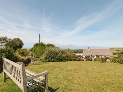 a wooden bench sitting in the grass in a yard at Honeycroft in Boscastle