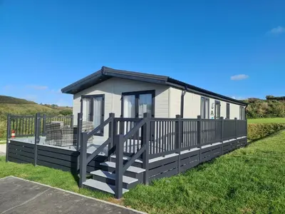 a small cottage with a black and white deck at Mawgan Pads Mawgan Porth in Mawgan Porth