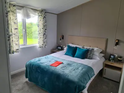 a bedroom with a bed with blue pillows and a window at Mawgan Pads Mawgan Porth in Mawgan Porth
