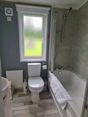 a bathroom with a toilet and a tub and a window at Mawgan Pads Mawgan Porth in Mawgan Porth