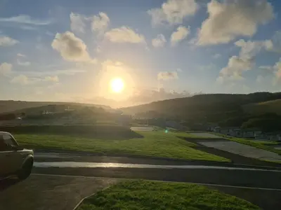 a car driving down a road with the sunset in the background at Mawgan Pads Mawgan Porth in Mawgan Porth