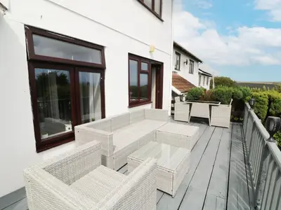 a balcony with wicker chairs and a table at 12 Claremont Falls in Looe