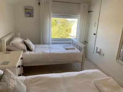 a bedroom with two beds and a window at Little Karenza is the perfect Cornish getaway in Saint Anthony