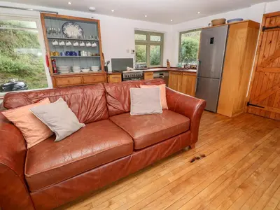 a brown leather couch in a kitchen with a refrigerator at Porth Farm Annexe in Newquay