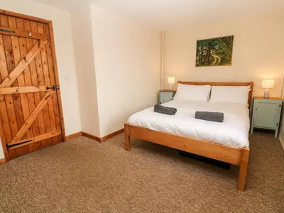 a bedroom with a bed and a wooden door at Porth Farm Annexe in Newquay