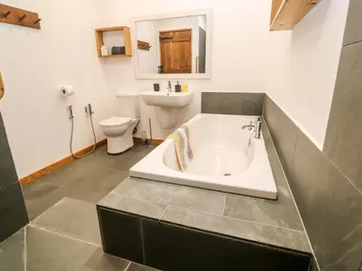 a bathroom with a tub and a toilet and a sink at Porth Farm Annexe in Newquay