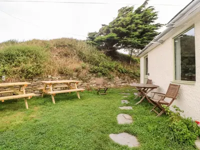 a picnic table and benches next to a house at Porth Farm Annexe in Newquay