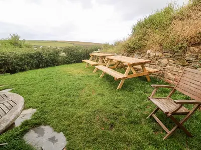 a row of picnic tables and chairs on the grass at Porth Farm Annexe in Newquay