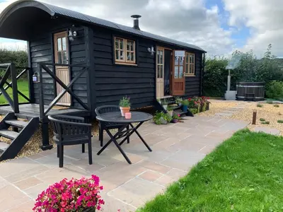 a black tiny house with a table and a patio at Daisy Park Shepherds Hut in Looe