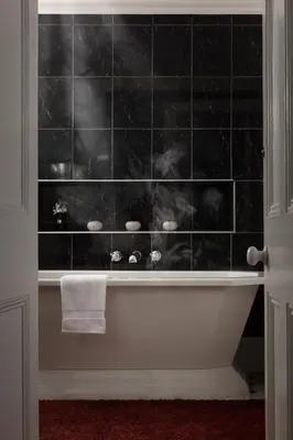 a bathroom with a bath tub with a black tiled wall at Penarwyn House in Par