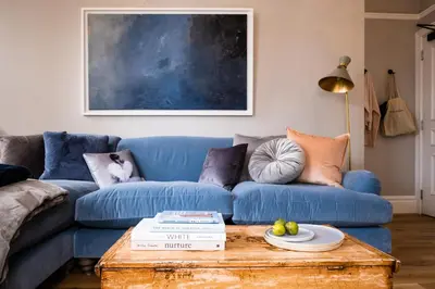 a blue couch in a living room with a table at Host St Ives in St Ives