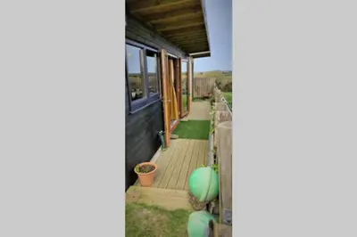 a house with a wooden porch and a fence at The Bolt Hole in St Merryn