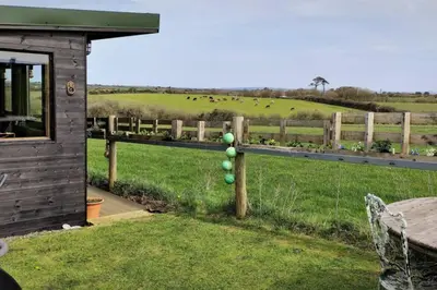 a fence with green eggs on it next to a field at The Bolt Hole in St Merryn