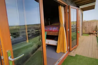 a door to a room with a bed on a balcony at The Bolt Hole in St Merryn