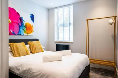 a bedroom with a bed with yellow and white pillows at Central, stylish 3 bed apartment with sea views in Newquay