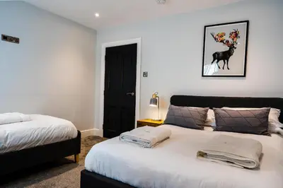 a bedroom with two beds and a picture of a horse on the wall at Central, stylish 3 bed apartment with sea views in Newquay